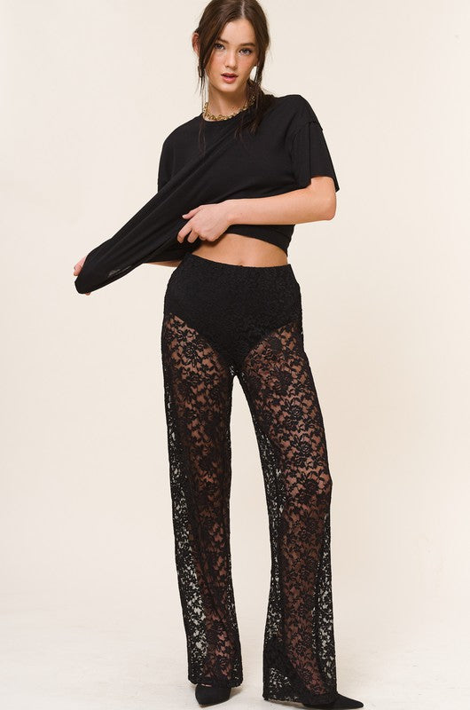 Model is wearing Black Lace Ruby Pants with black tee and heels. front view 