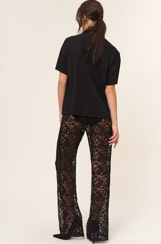 Model is wearing Black Lace Ruby Pants with a matching black tee and black heels. Back view of the model. 