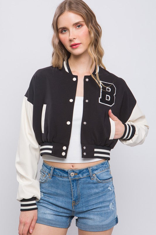 model is wearing Black Varsity Crop Jacket with a white top and denim shorts 
