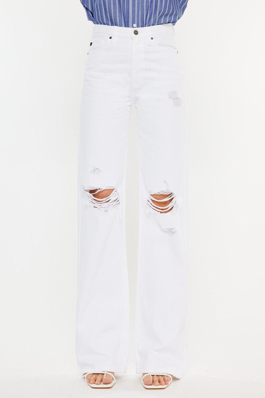 Model is wearing White High Rise Flare Jeans with white sandals. Close up view of the pants detail 