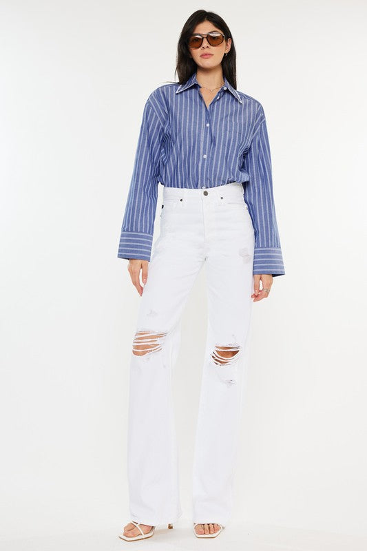 Model is wearing White High Rise Flare Jeans with white heels and a blue stripped shirt, the model is also wearing chic sunglasses. Front view 