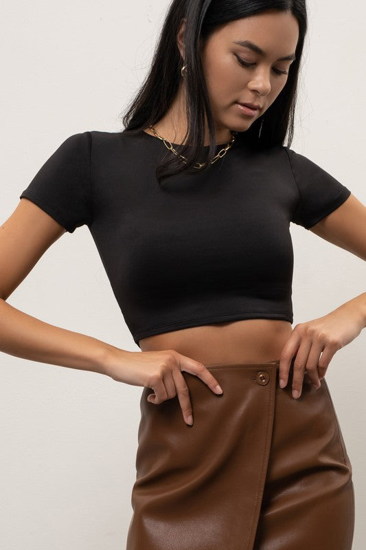 model wearing Black Reversible Round Neck Crop Top with gold necklace and brown leather mini skirt
