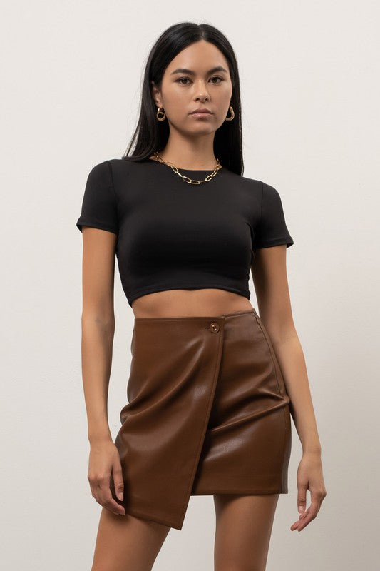 model is wearing Black Reversible Round Neck Crop Top with a brown eather mini skirt