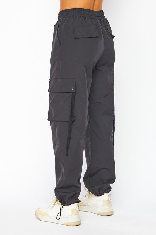 model is wearing Black Parachute Cargo Pocket Pants and white sneakers. Back view 