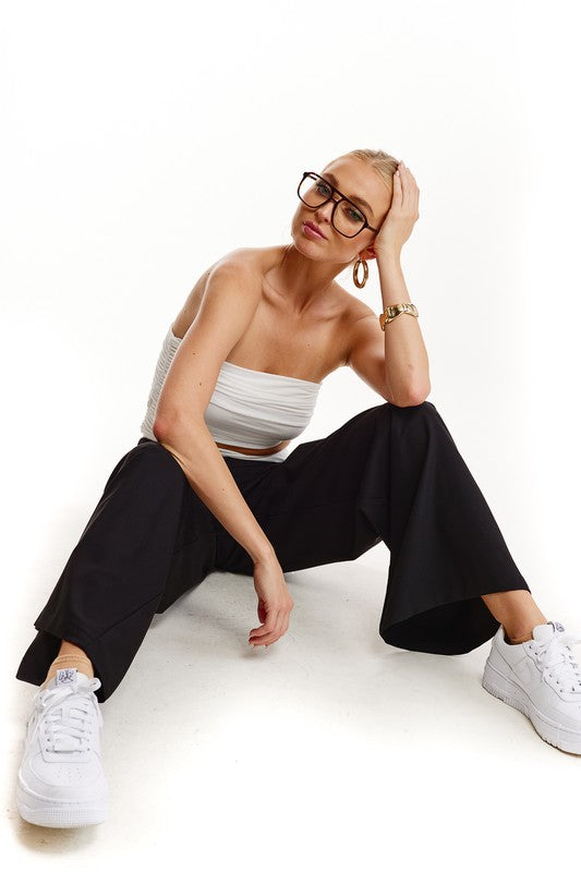 White Strapless cut out crop top with black pants with gold hoop earrings and black glasses and women's white sneakers