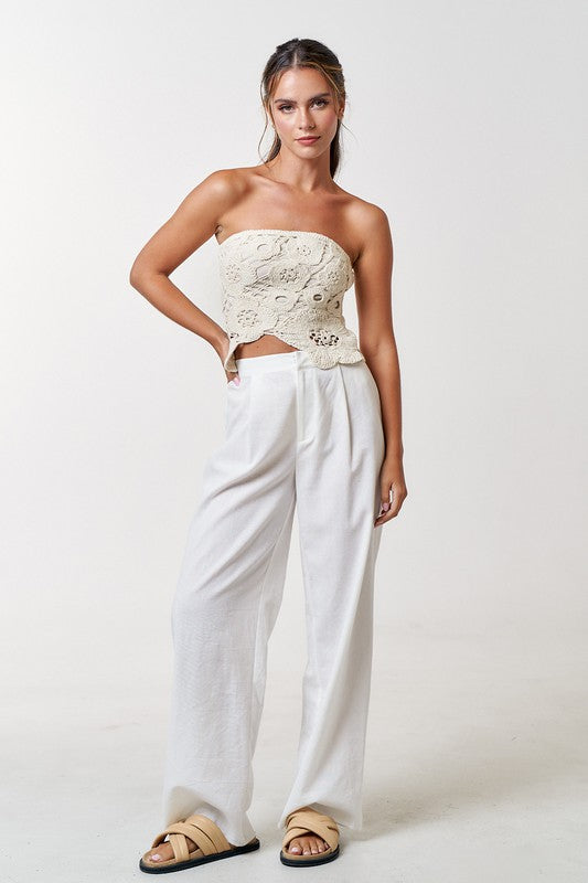 Model is wearing Natural Crochet Flyway Tube Top with white trousers and beige slide on sandals 