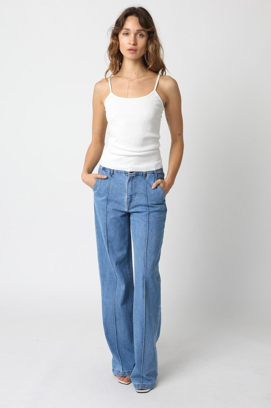 model is wearing Denim Jane Flare Pants and white tank top with white heels 