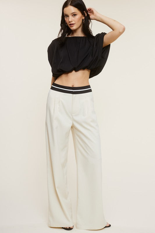 model wearing a black blouse and cream talbot trousers contrast of the waistband and black heels 