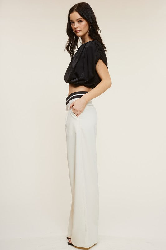 Side view of the model wearing Cream Talbot Trousers and a black blouse