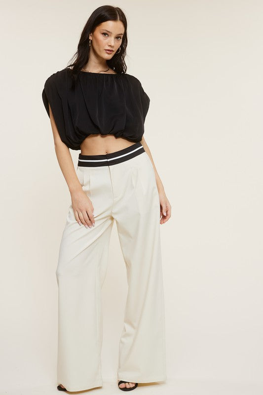 Model wearing a Cream Talbot Trousers with a sleeveless black blouse and black sandals 