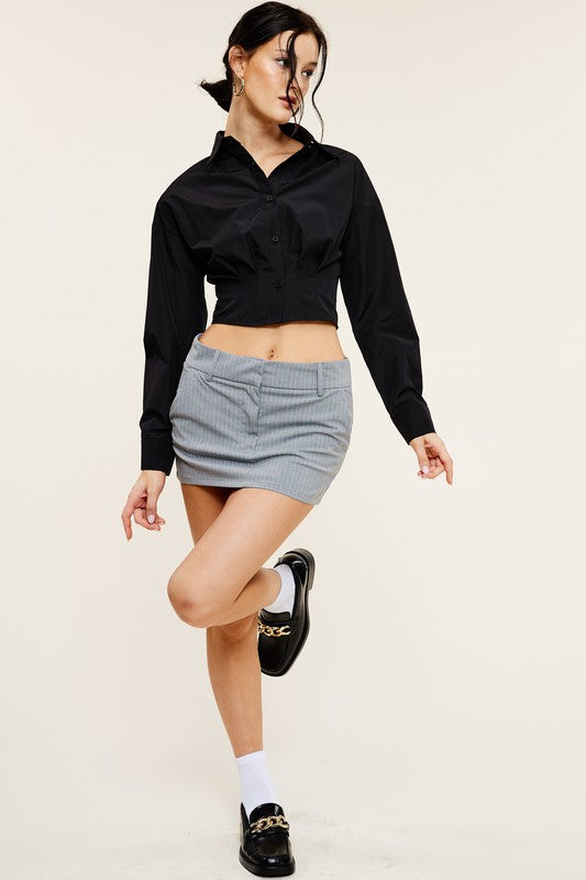 model is wearing Black Giselle Shirt with a grey mini skirt and black loafers 