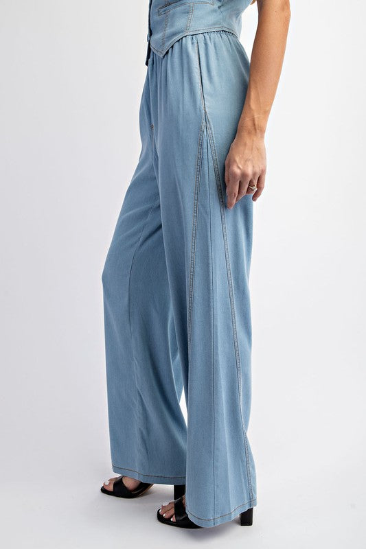 Model is wearing Denim Elastic Waist Pants with matching pants and black heels, Side view of the hem 