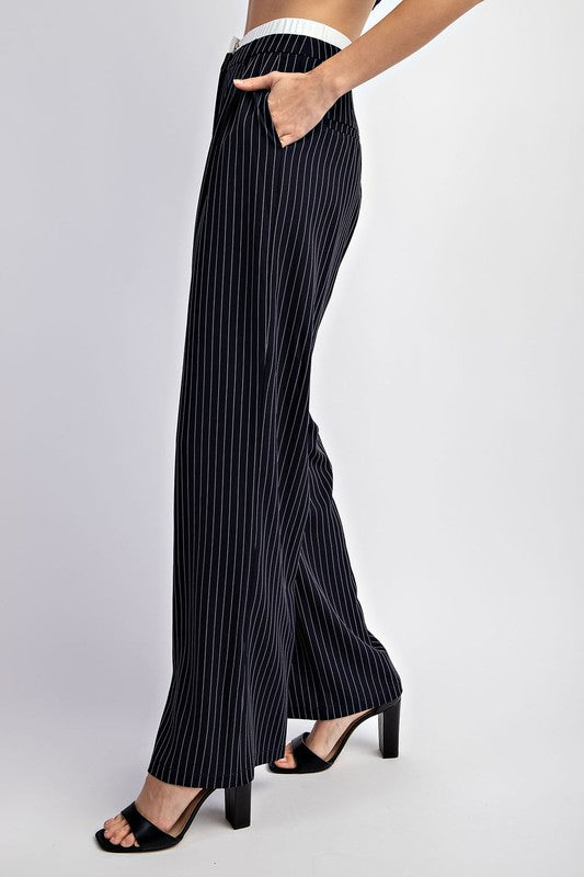 Model is wearing Navy Pinstriped Tailored Trousers, close up side view of the hem and pockets, with black heels 