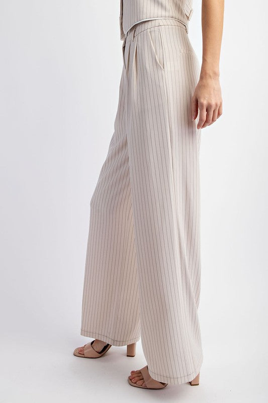 Model is wearing Beige Pinstriped Tailored Trousers with  beige heels sandals, side view showing the hem and pockets of the pants 