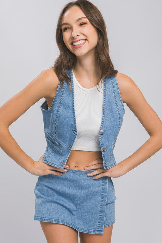 model is wearing the Light Denim Buttoned Vest Top open with a white crop top and matching denim skort 