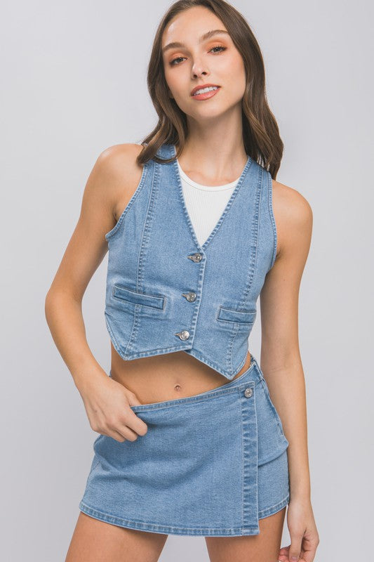 model is wearing Light Denim Buttoned Vest Top with a white top underneath and a matching denim mini skort