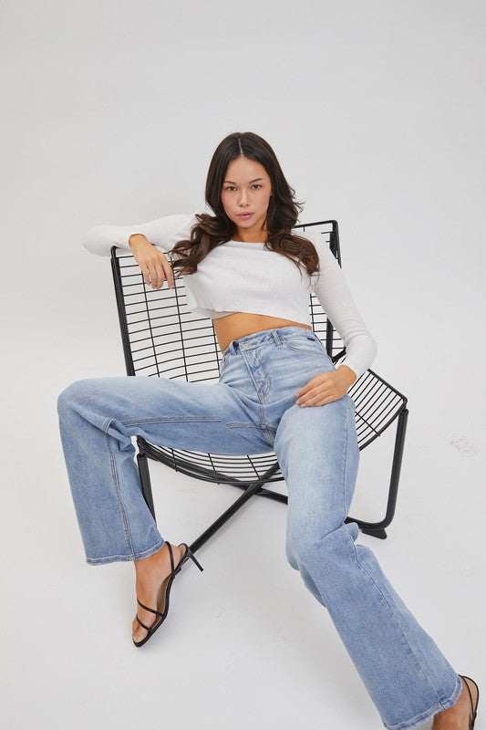 model is sitting wearing a white long sleeve top with Denim Re-positioned Closure Dad Jean and black heels sandals 