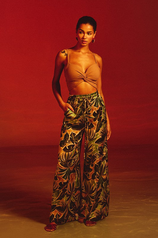 Model is wearing Tropical Ibiza Pull On Pants with slide sandals and a camel twisted knot front crop top 