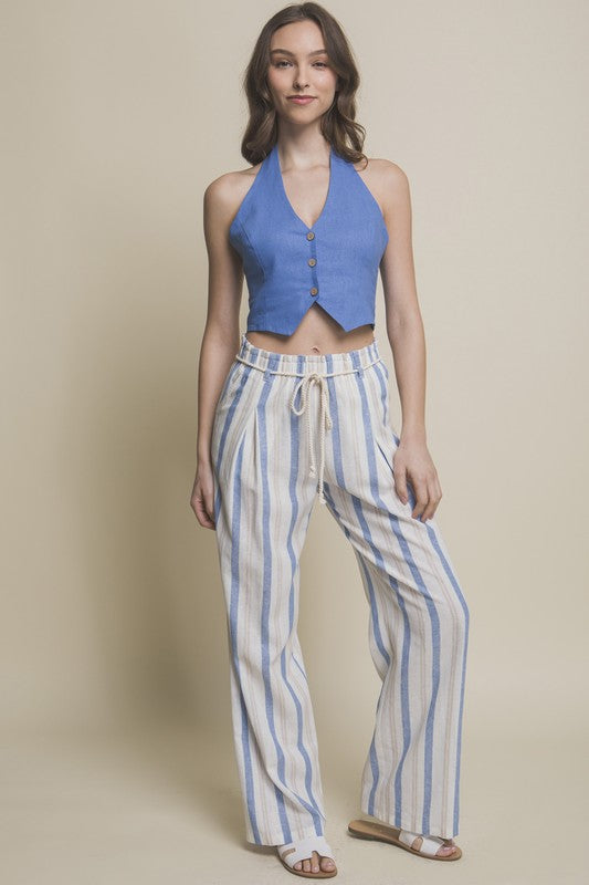 Model is wearing Blue Linen Cropped Vest with striped pants and white slide sandals 