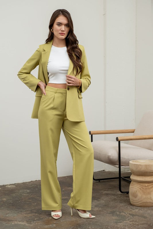 model is wearing Kiwi High Waisted Wide Leg Slacks with a white tank top and matching kiwi blazer with white high heels 