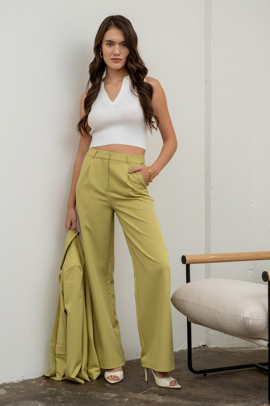 model is wearing Kiwi High Waisted Wide Leg Slacks with a white blouse and white heels