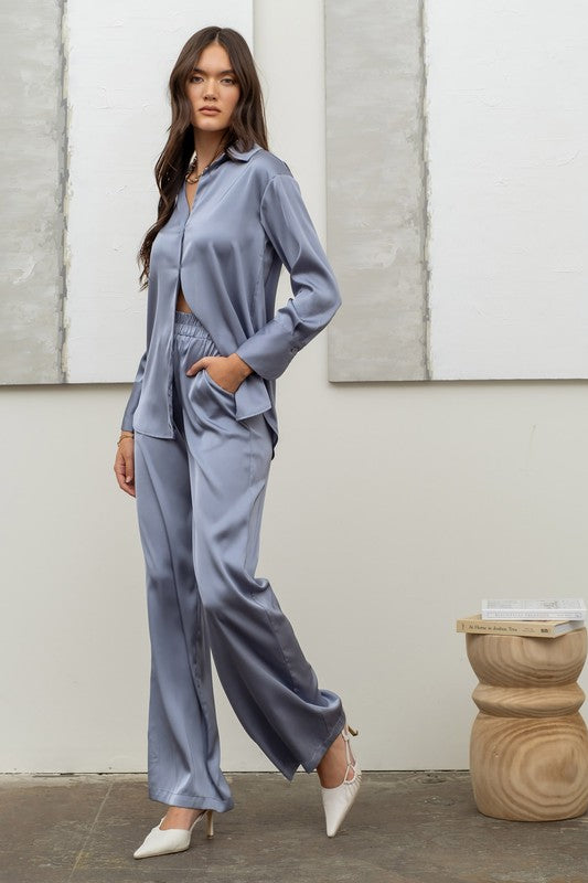 model is wearing Dusty Blue Satin Bell Bottom Pants  with matching satin and white heels 