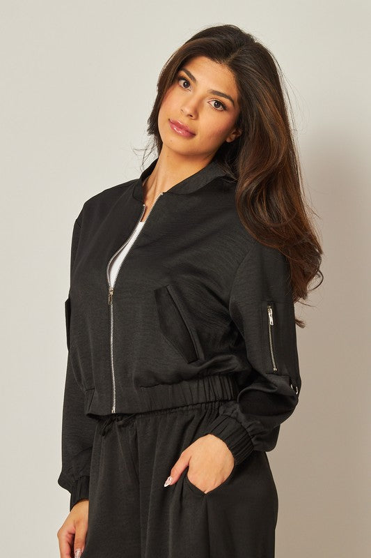 model wearing the Black Satin Bomber Jacket with a white tee underneath and a matching black pants