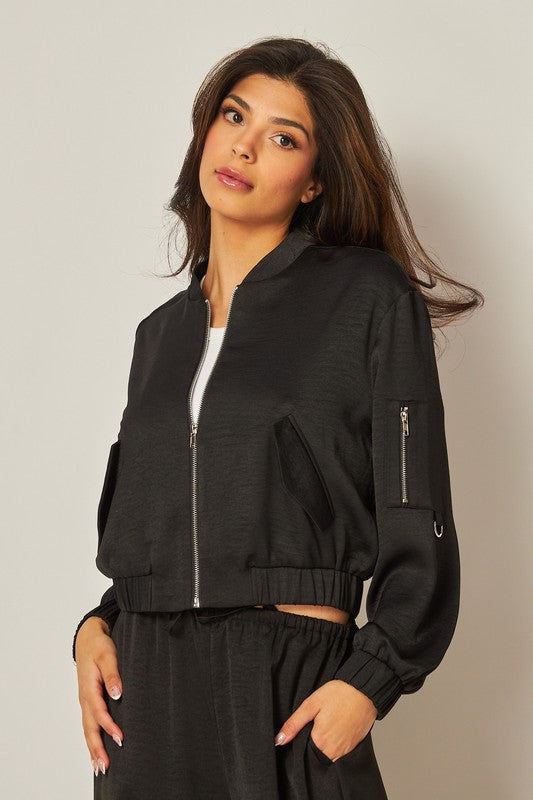 model wearing Black Satin Bomber Jacket with matching black pants and white top 