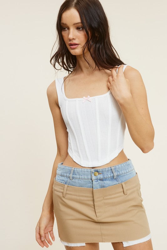 Maddy White Corset Top with small baby pink bow in middle top with jean skirt that jean and beige with white pockets coming out in the bottom