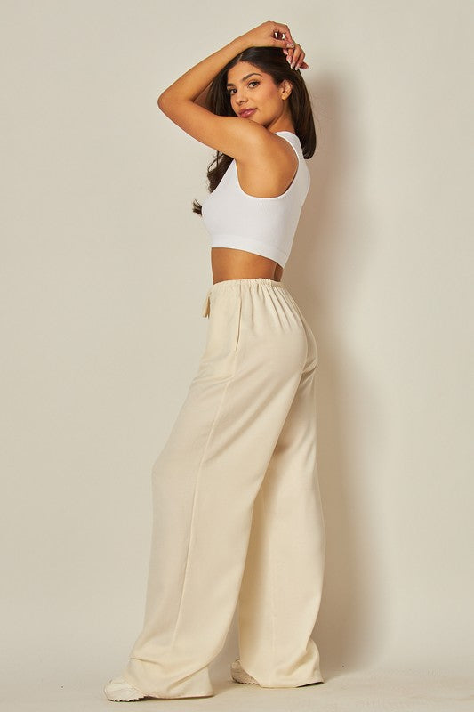 Model is wearing Ivory Satin Wide Leg Pants with a basic white top 