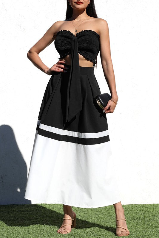 model is wearing Black Smocked Skirt Set with beige heels and black clutch bag