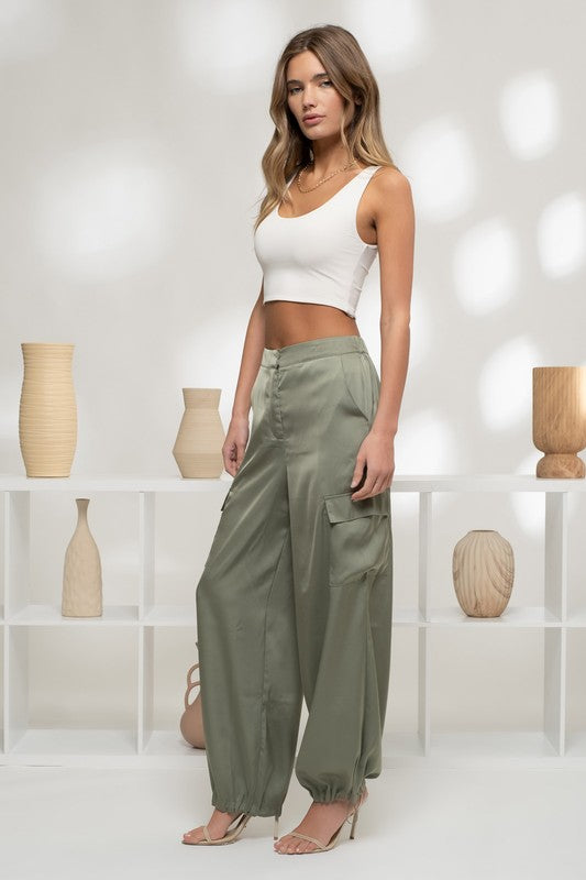 model is wearing Olive Satin Cargo Jogger Pants with a white tank top and beige heels 