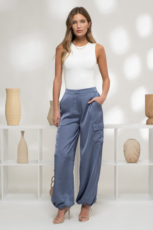 model is wearing Denim Blue Satin Cargo Jogger Pants and white bodysuit  and beige heels 