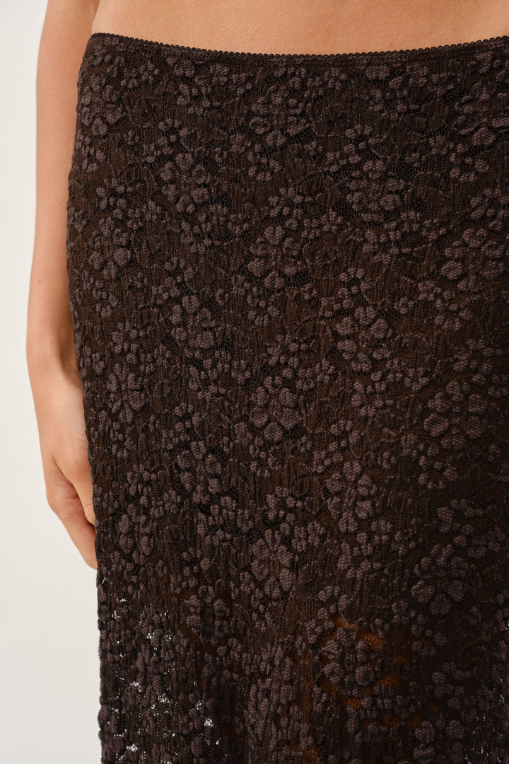 Close-up of the all-over brown floral textured lace fabric at the maxi skirt waist