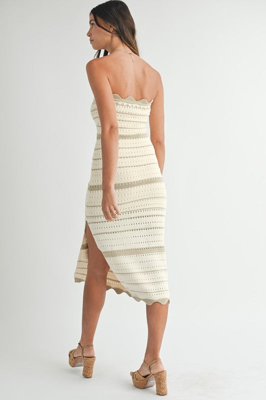 Rear angle showing the back view of the strapless knit dress with a high slit and scalloped hem, paired with cork heels.