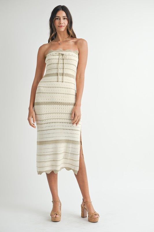 Model facing forward with both hands at her sides, showcasing the full front design and mid-calf length of the crochet knit dress.
