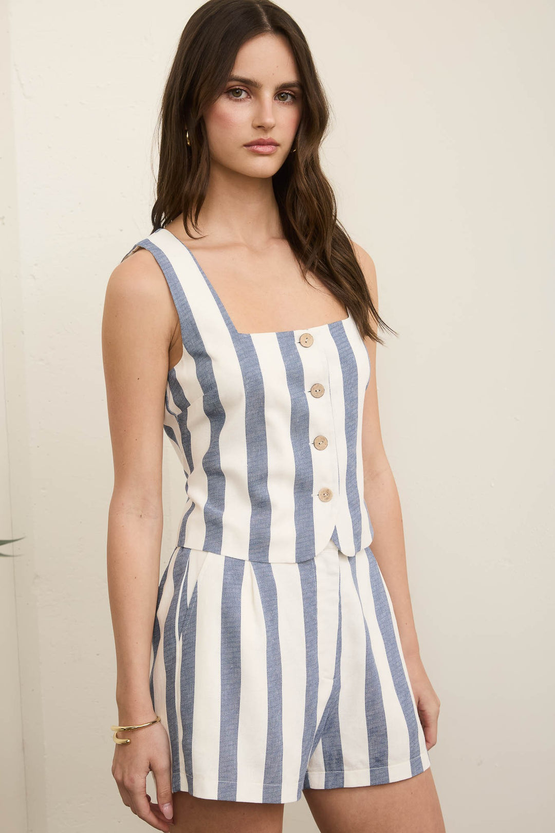 Woman wearing a blue and white striped romper against a plain background