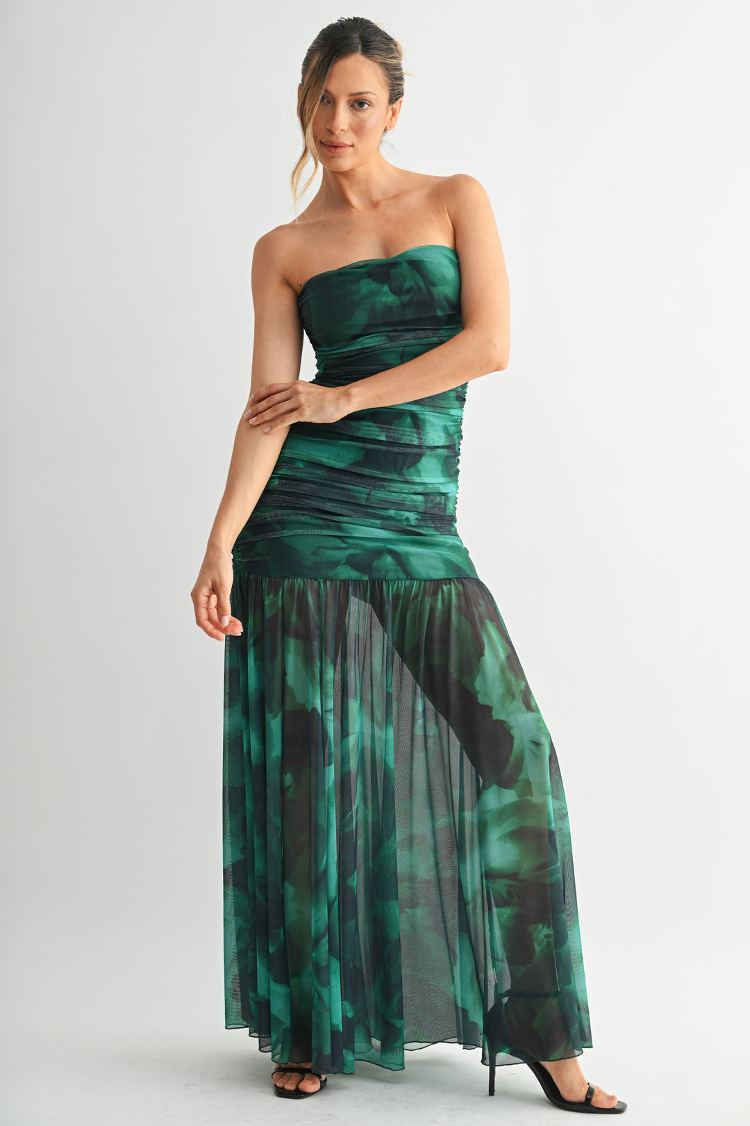 Woman wearing a strapless green and black patterned dress on a white background