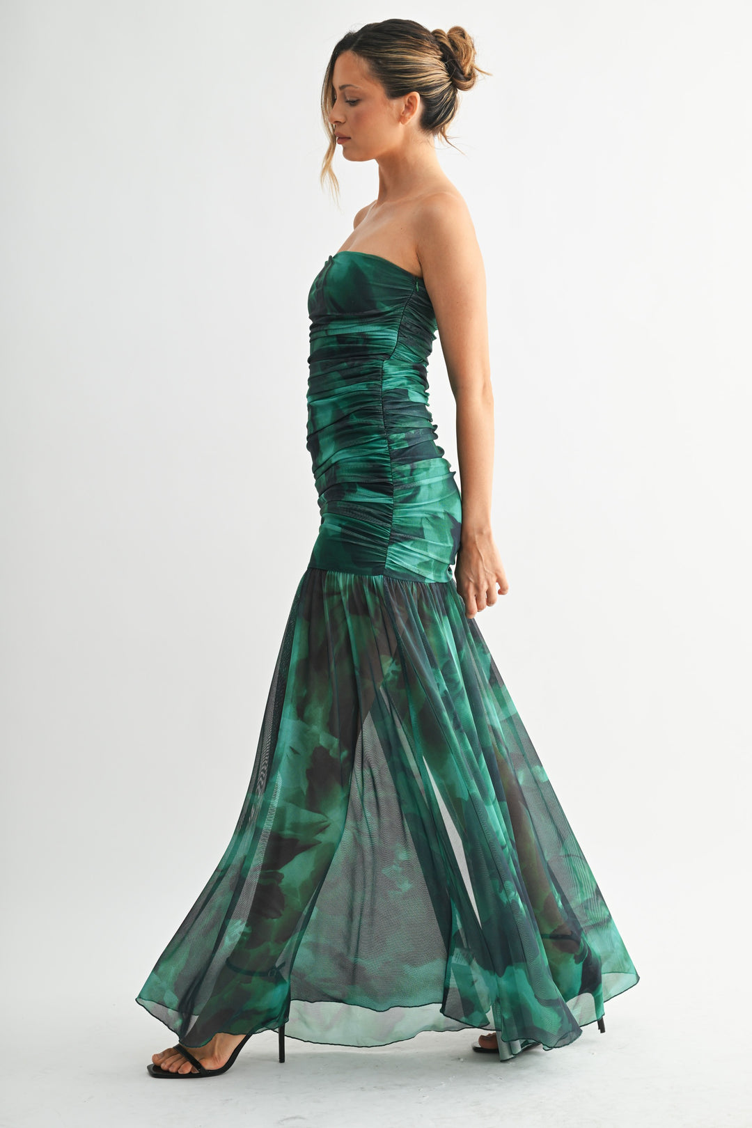 Woman wearing a strapless green evening gown on a white background