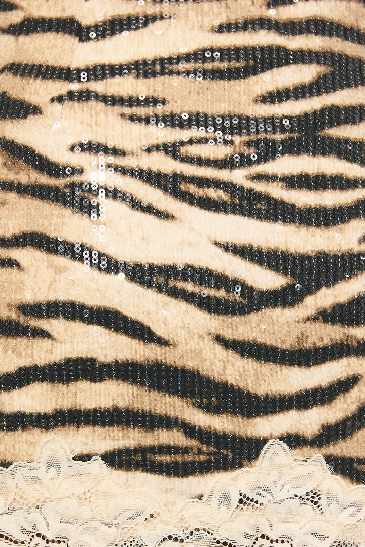 Close-up of the beige and black tiger print sequins and cream lace trim on the mini skirt