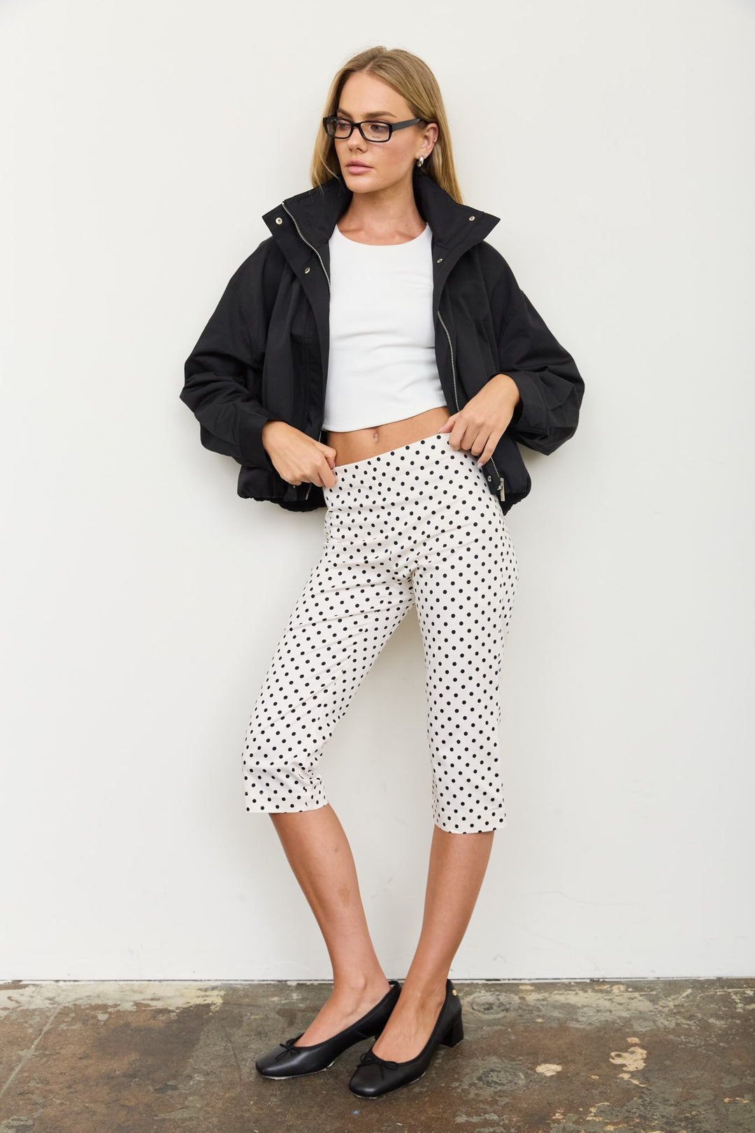 Full-length view of the black mock neck zip jacket with white polka dot pants, a casual fall outfit