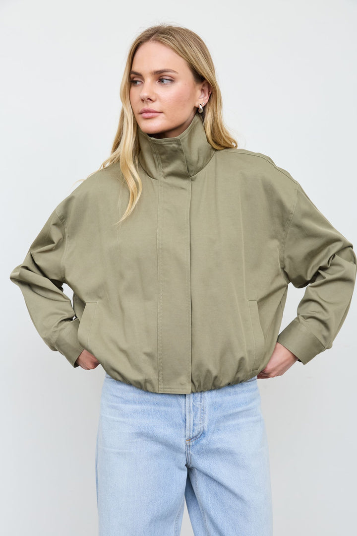 Front view of the olive mock neck zip jacket with light blue jeans, a casual fall outfit