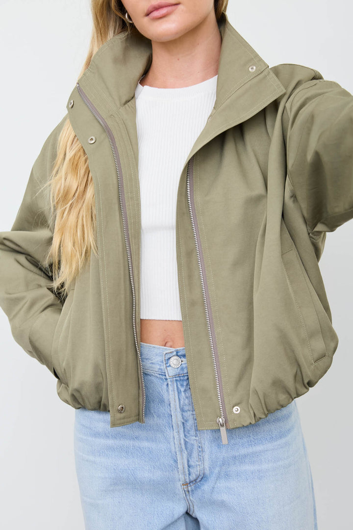 Close-up of the Olive Mock Neck Zip Jacket with silver two-way zipper and snap collar over a white tee