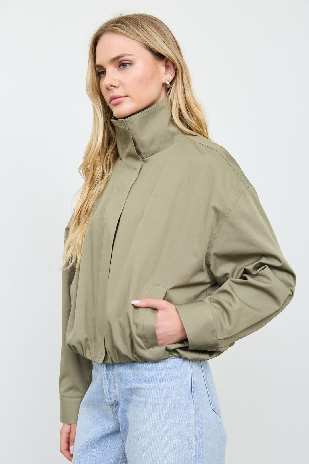 Three-quarter view of the olive mock neck zip jacket with the collar zipped up, a fall outerwear look