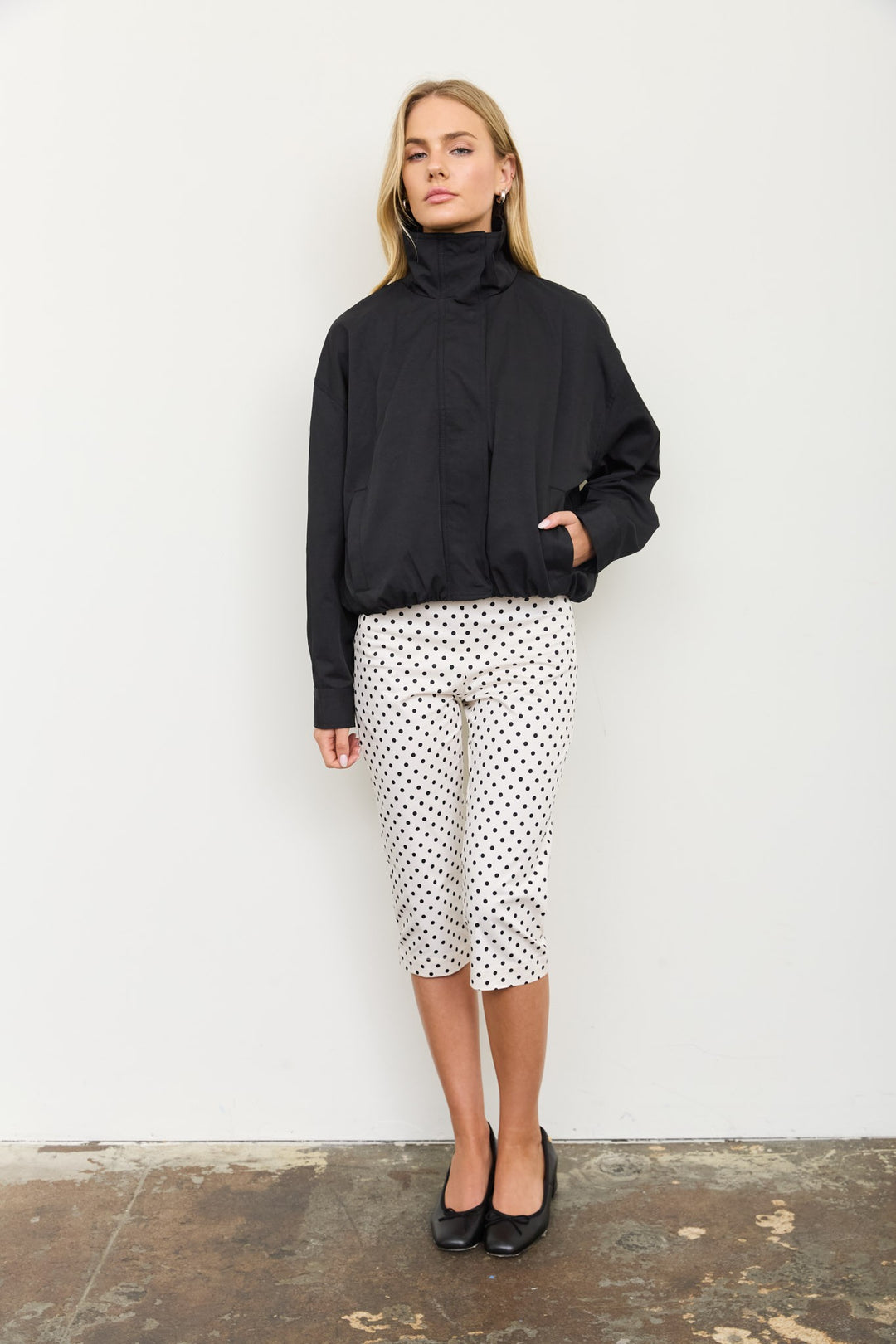 Front view of the black mock neck zip jacket zipped up with hands in pockets, a Thanksgiving weekend look