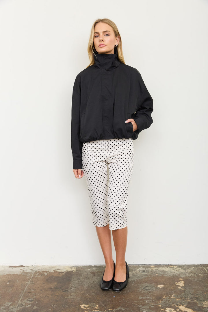 Front view of the black mock neck zip jacket zipped up with hands in pockets, a Thanksgiving weekend look