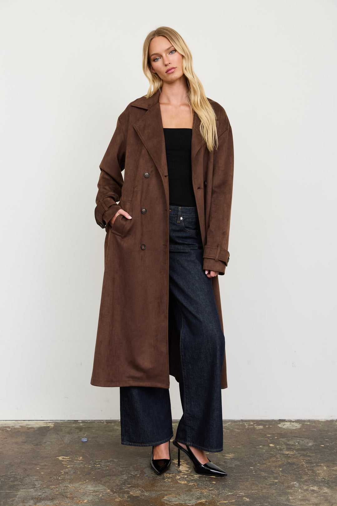 Front view of the dark brown suede double-breasted trench coat with dark wide-leg jeans and pumps