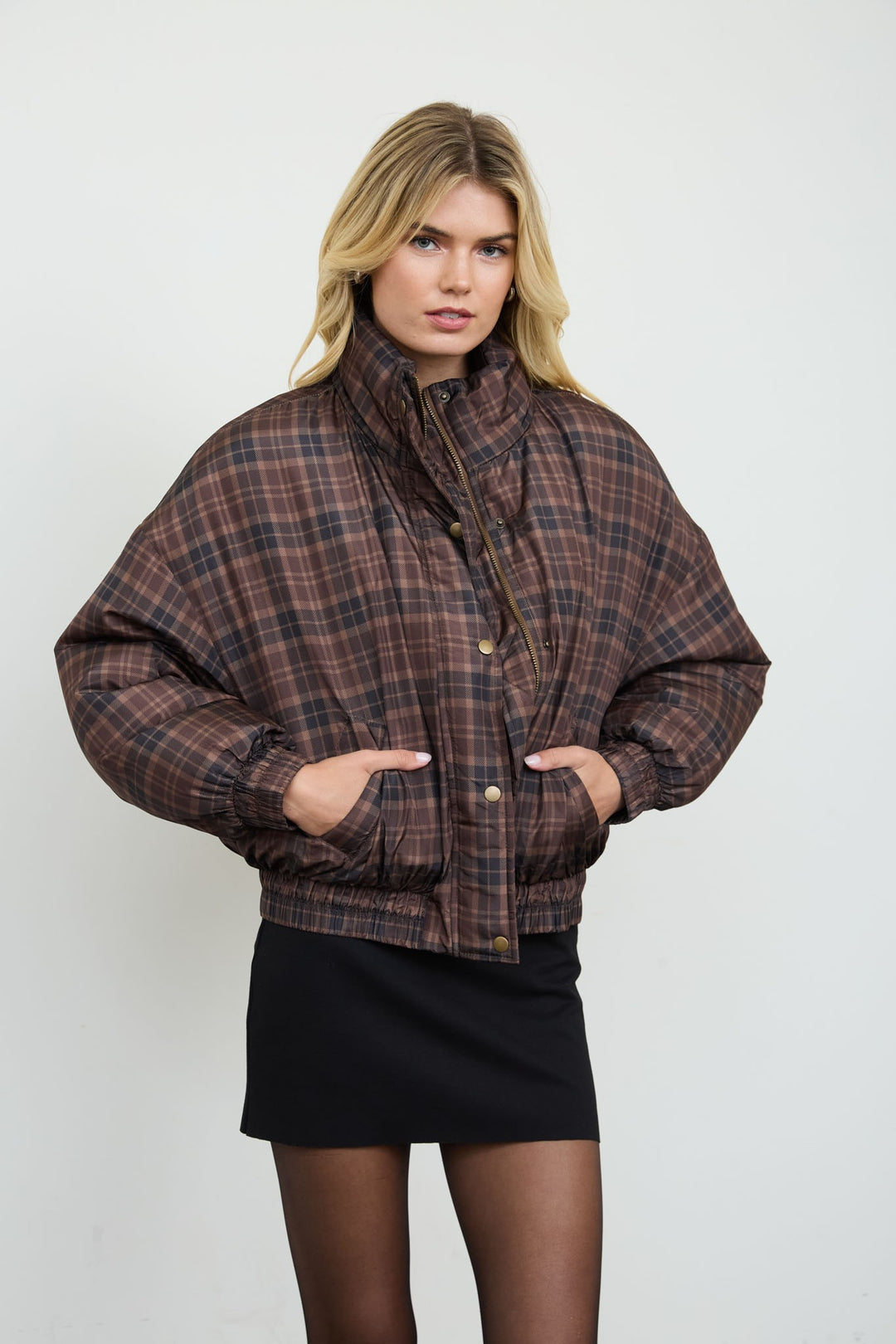 Front view of the Brown Plaid Cropped Puffer Jacket with funnel neck and black mini skirt, a fall outfit