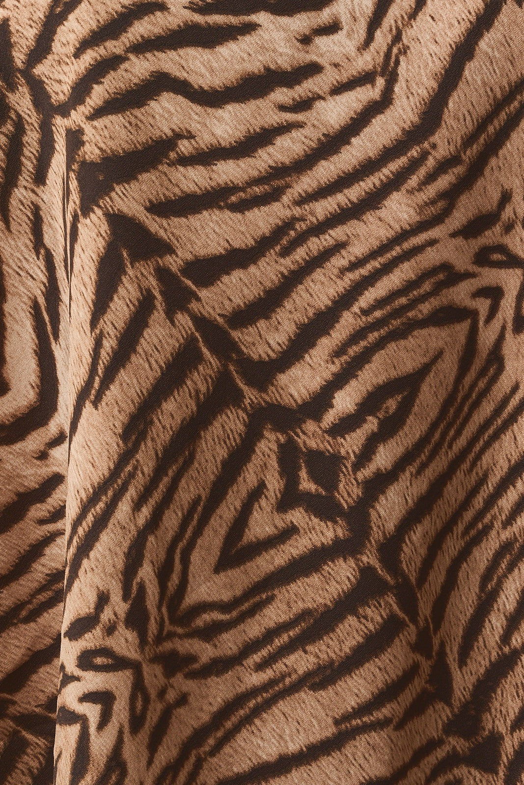 Close-up of the taupe and brown tiger print satin fabric of the shorts
