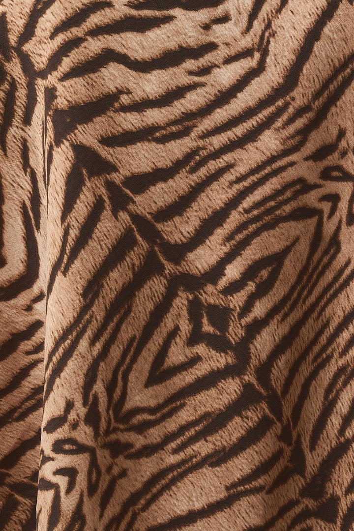 Close-up of the taupe and brown tiger print satin fabric of the shorts